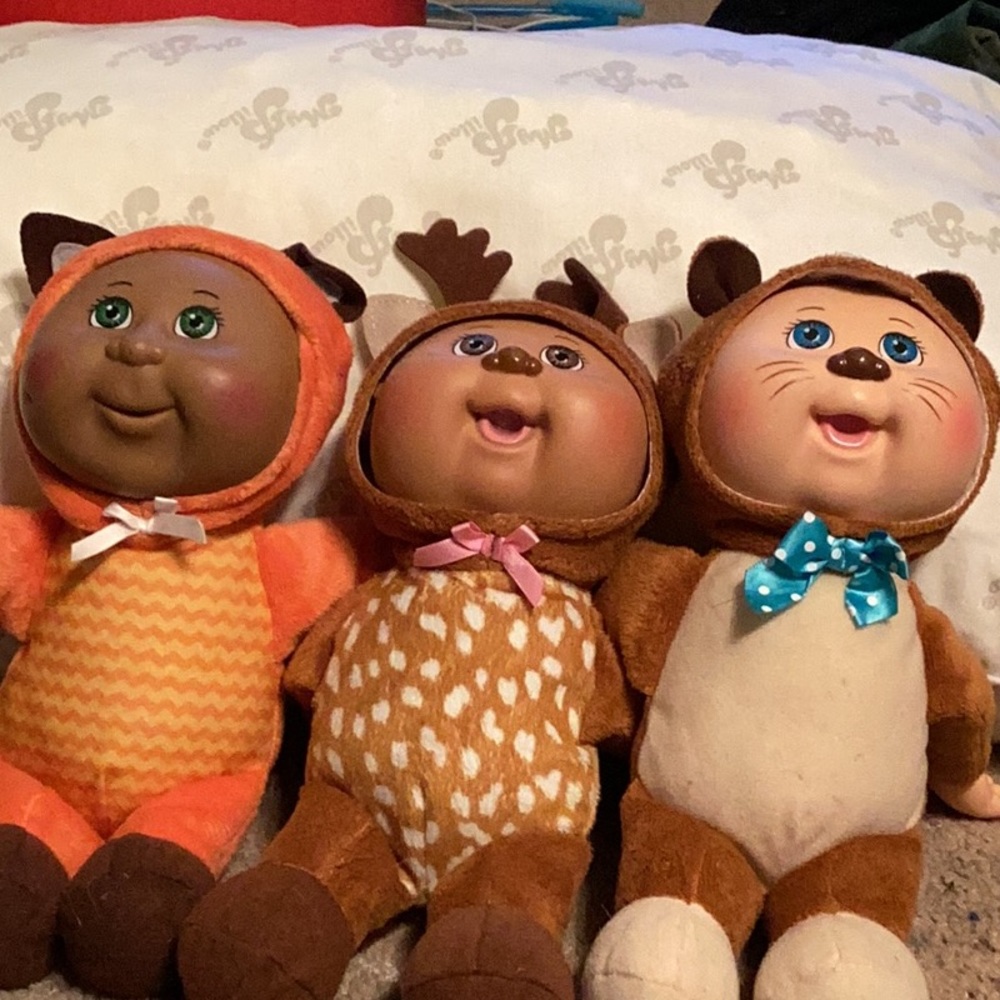 Three cabbage patch kids wearing woodland animal outfits